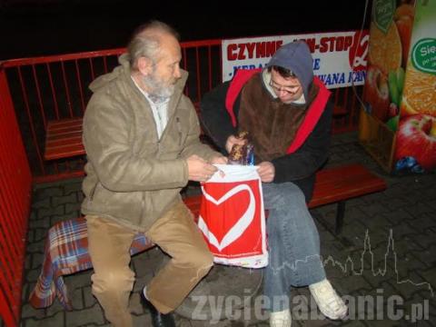 Marek Skrzymowski przekazuje paczkę żywnościową osobie bezdomnej