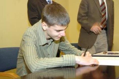 Mateusz Marynowski podpisuje odbiór nagrody.