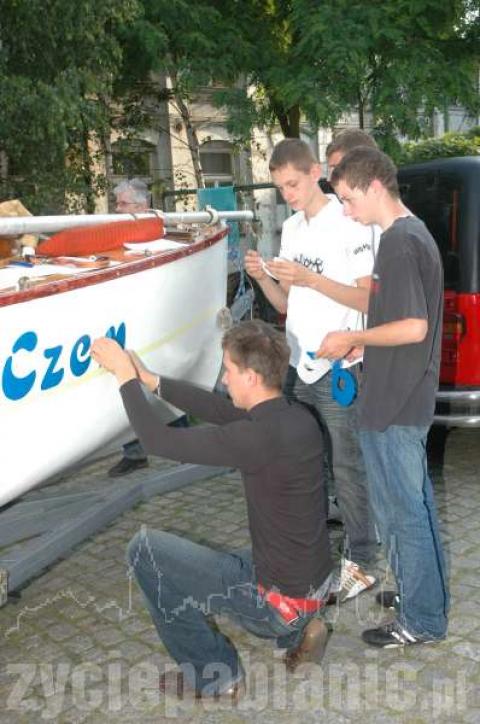 Członkowie klubu umieszczają napis "Czemu by nie" na kadłubie łodzi